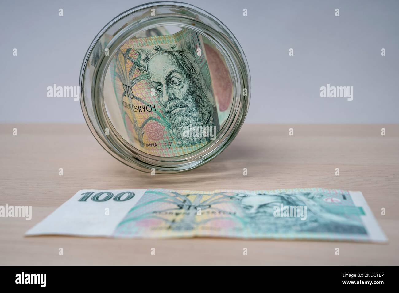 Banconote da 100 korun della Repubblica Ceca banconote in vasetto di vetro, risparmio di denaro, vasetto di vetro su scatole di banconote in contanti. Foto Stock