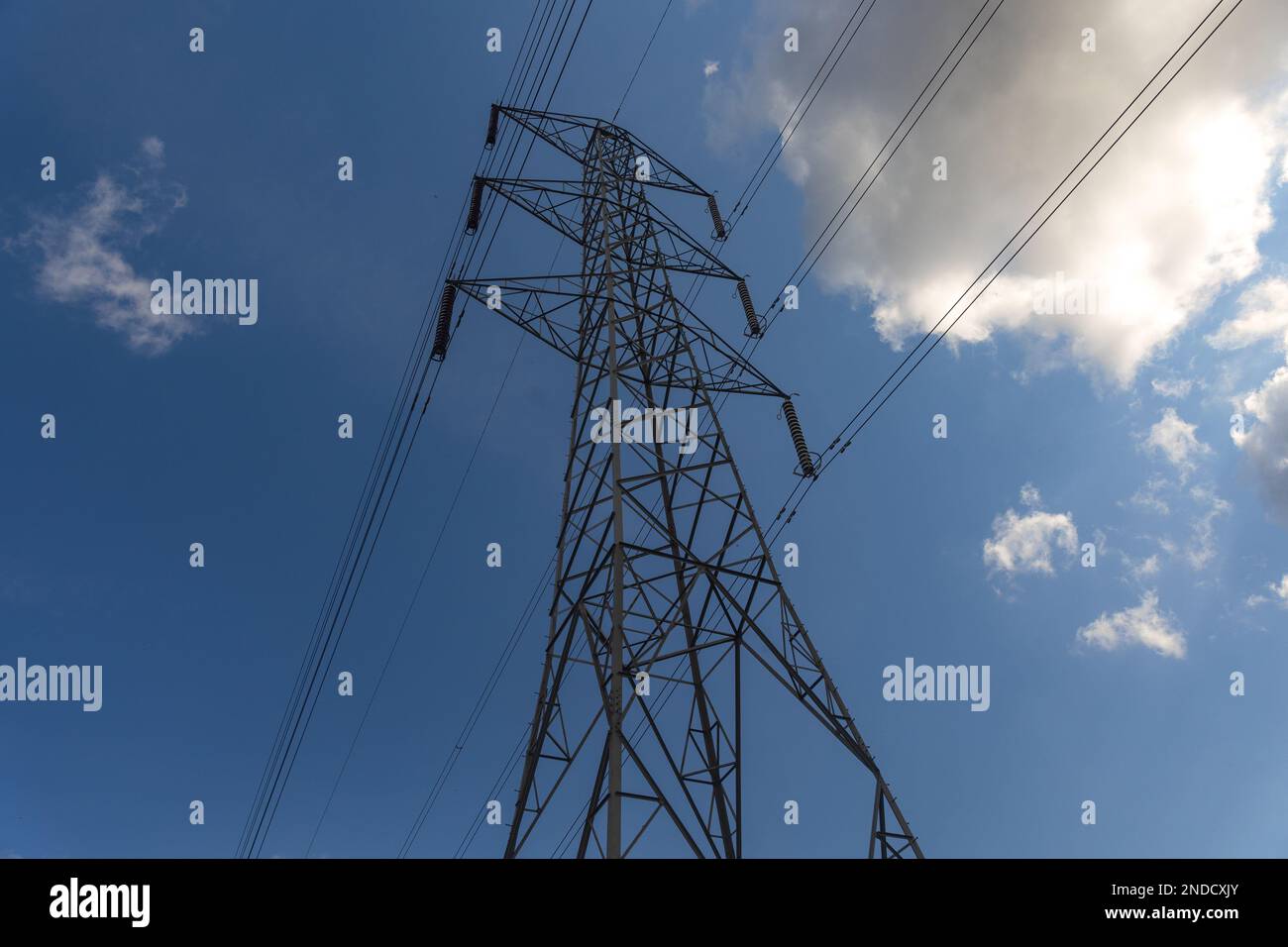 Un traliccio di elettricità e cavi contro un cielo di lue con nuvole Foto Stock