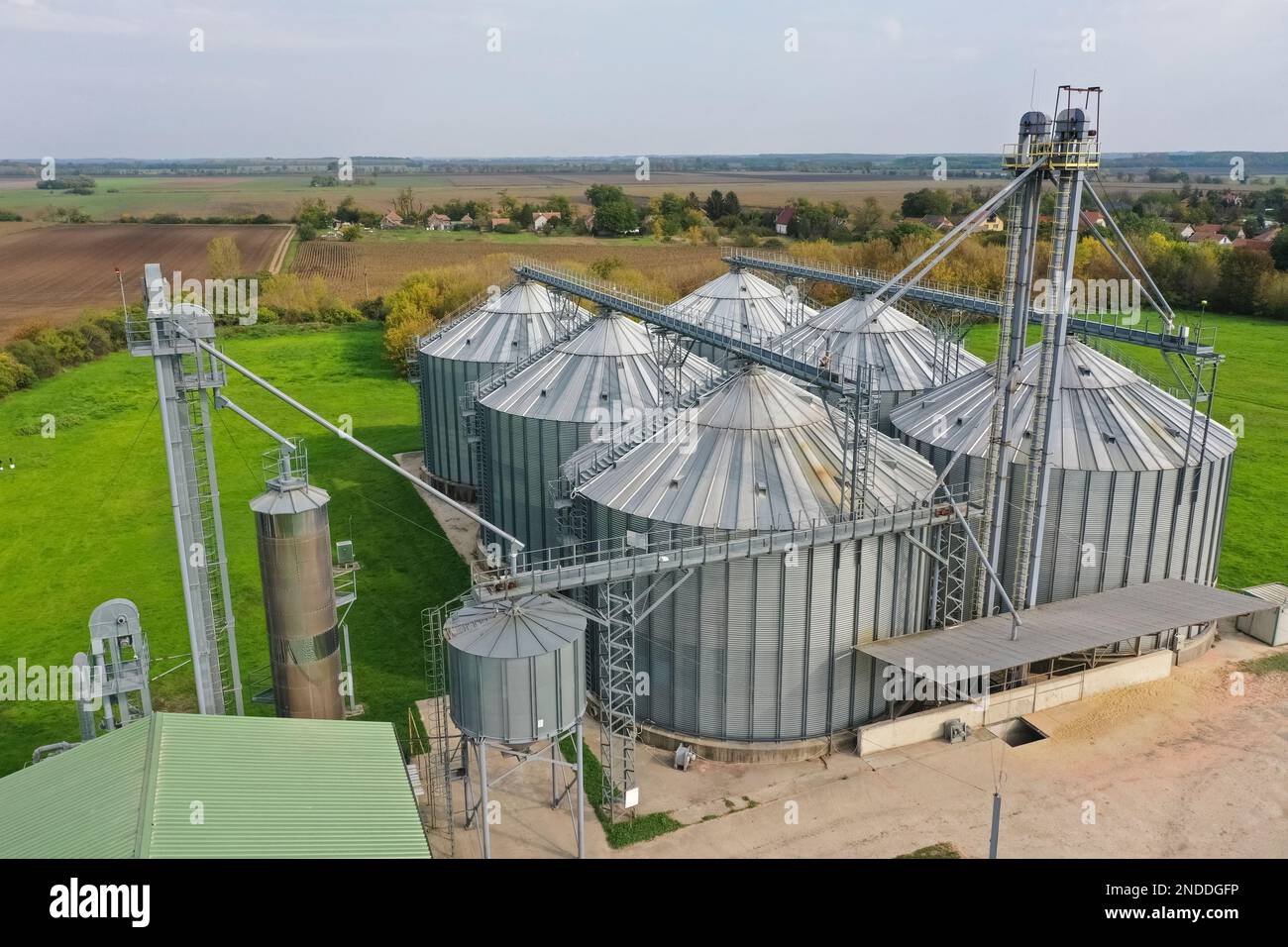 Silos agricoli sulla fattoria in autunno, vista ravvicinata drone. Granaio industriale, essiccatore elevatore, esterno dell'edificio, deposito ed essiccazione di grano, whe Foto Stock