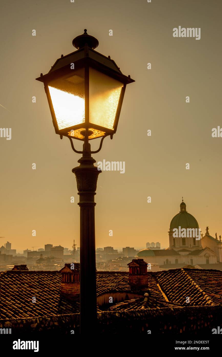 Antico lampione in ferro battuto illuminato con sullo sfondo la cattedrale  di Brescia Foto stock - Alamy