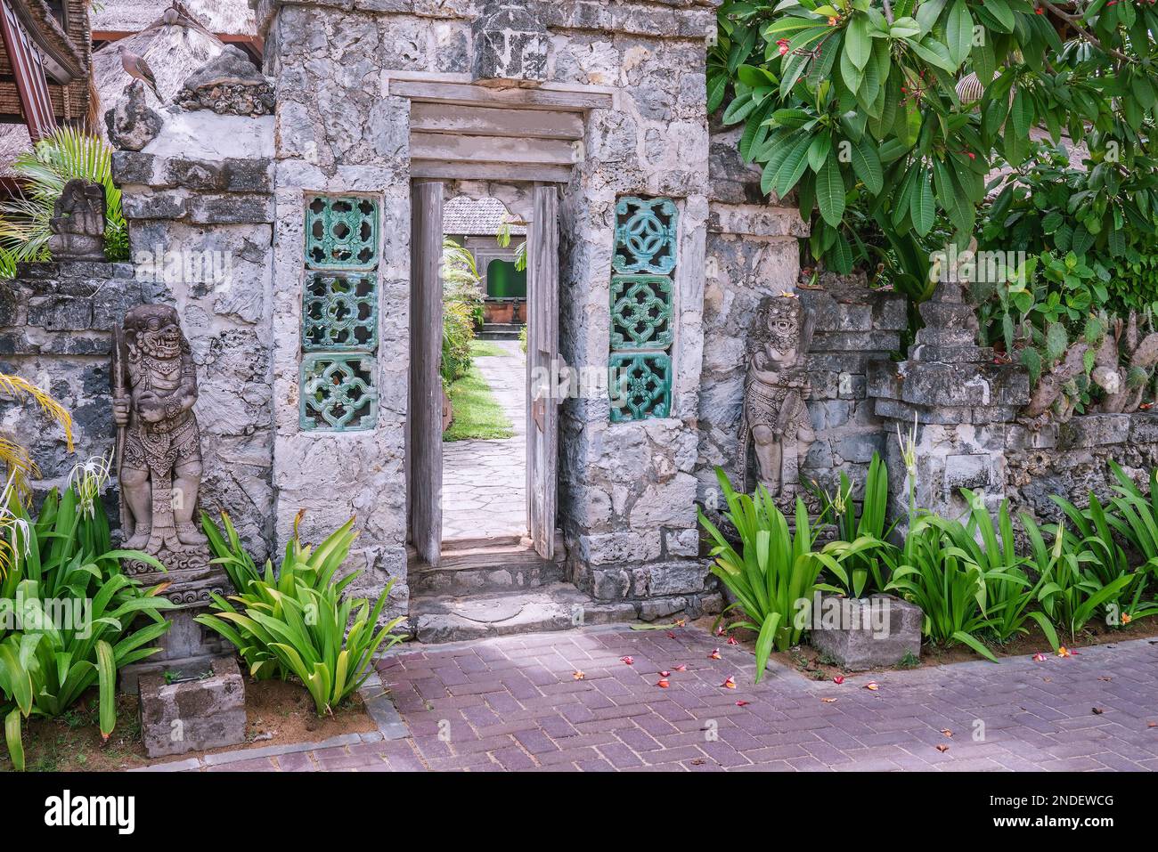 Aprire vecchie porte di ingresso in legno in pietra con due tradizionali statue di guardia balinesi, foto di strada Foto Stock