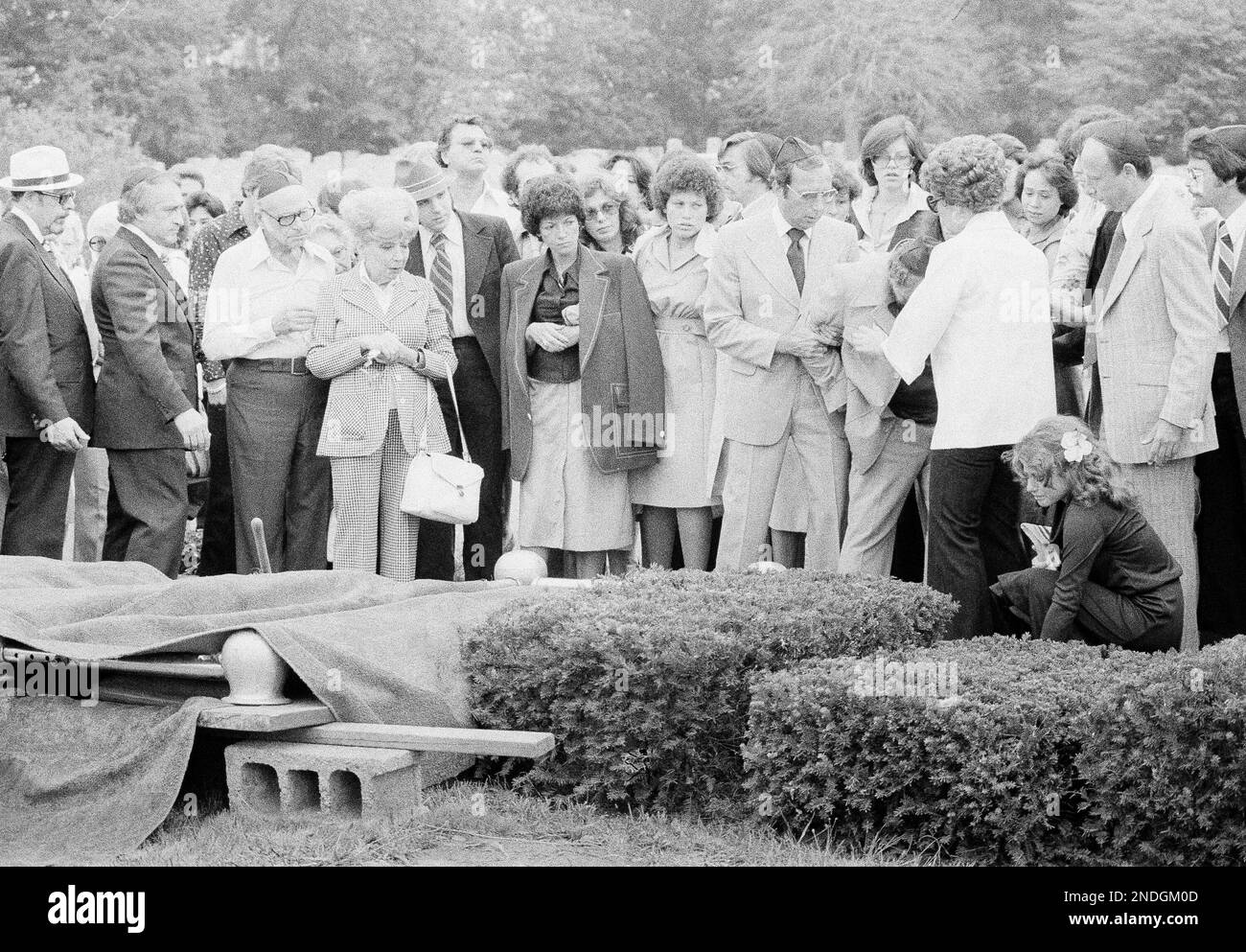 Sister, Ricki, bends to place flower on grave of Stacy Moskowitz, as