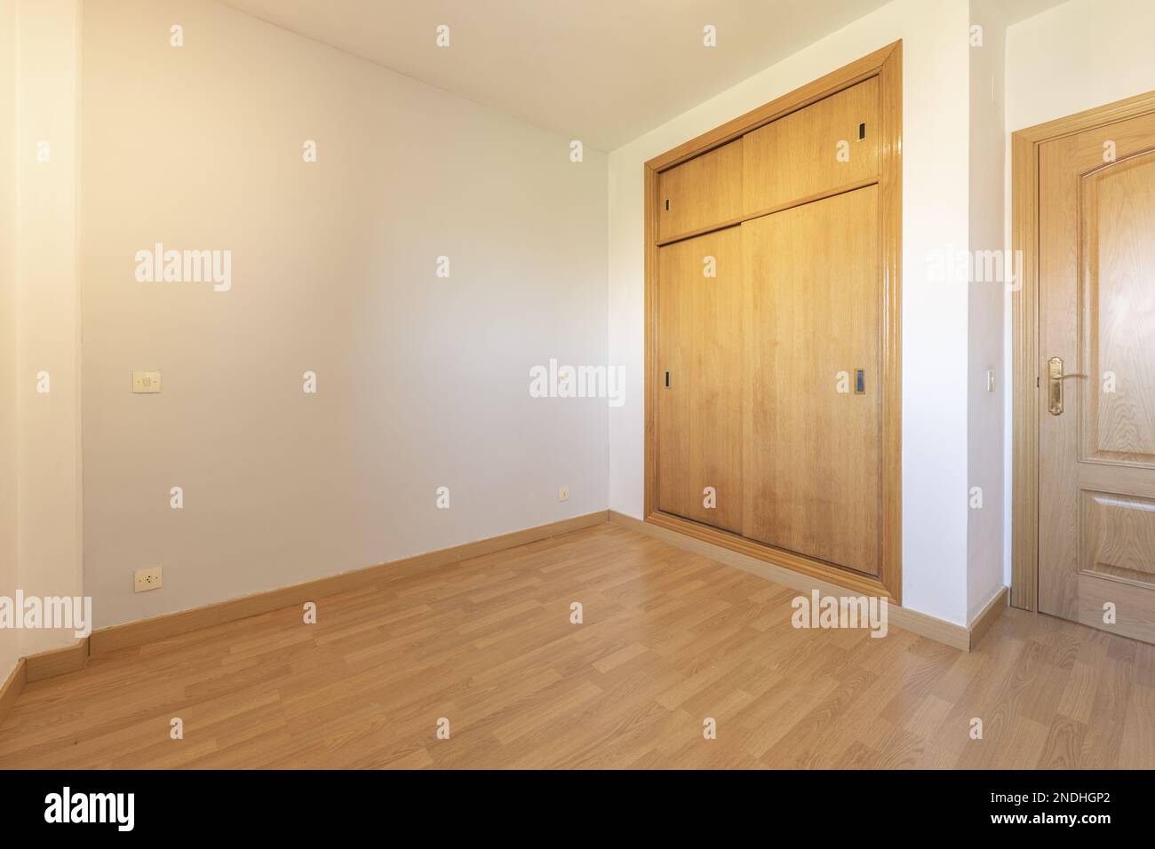 Camera vuota con armadio a muro con porte scorrevoli in legno chiaro e pavimento in legno galleggiante Foto Stock