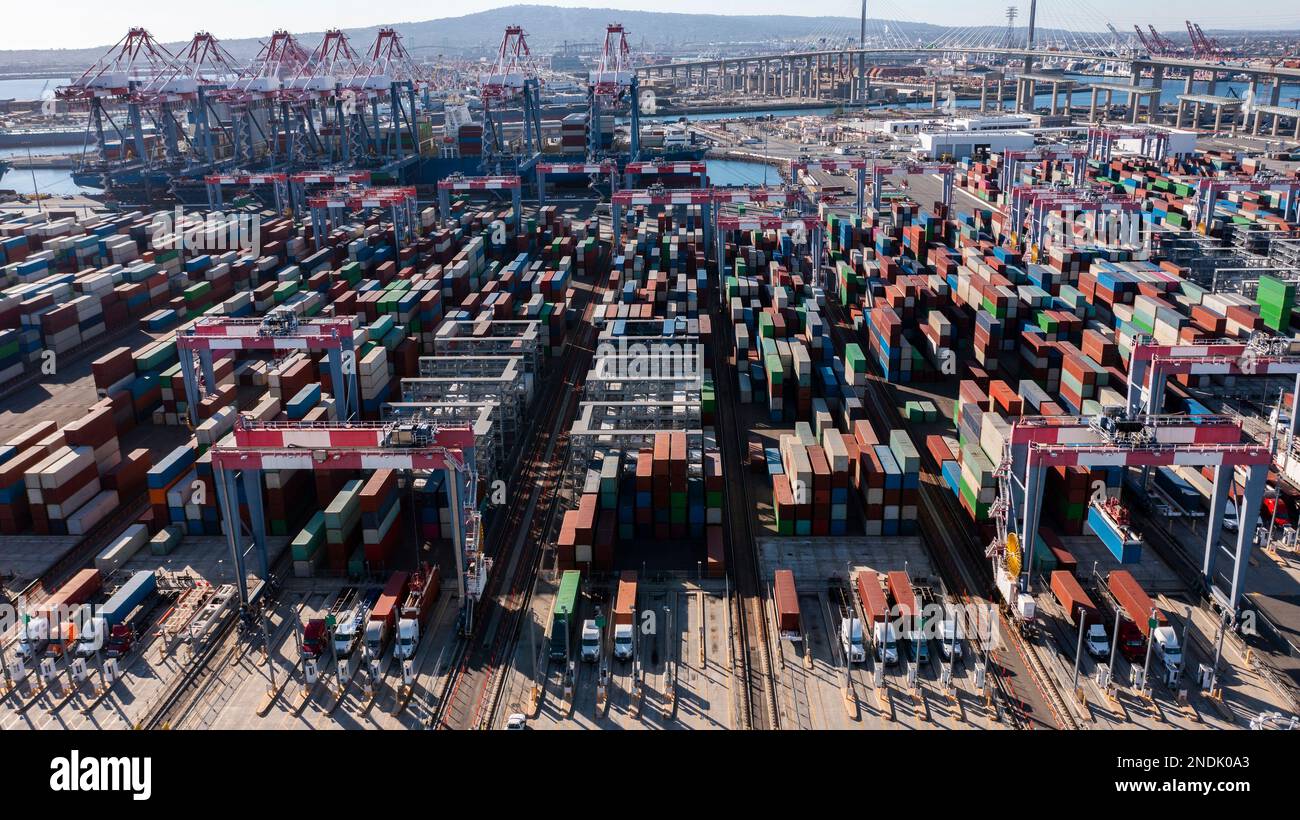 Vista aerea diurna di un cantiere intermodale di stoccaggio per la spedizione di container che scarica le navi in porto. Foto Stock