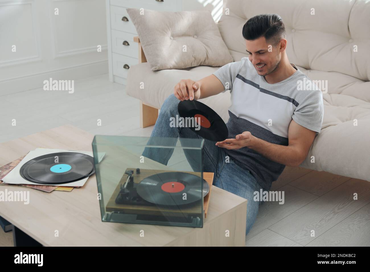 Un uomo felice che ascolta la musica con il giradischi a casa Foto Stock