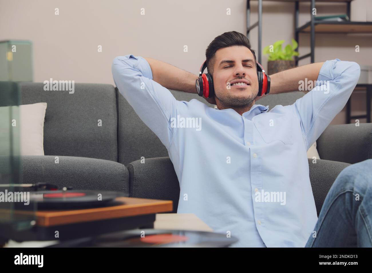 Un uomo felice che ascolta la musica con il giradischi a casa Foto Stock