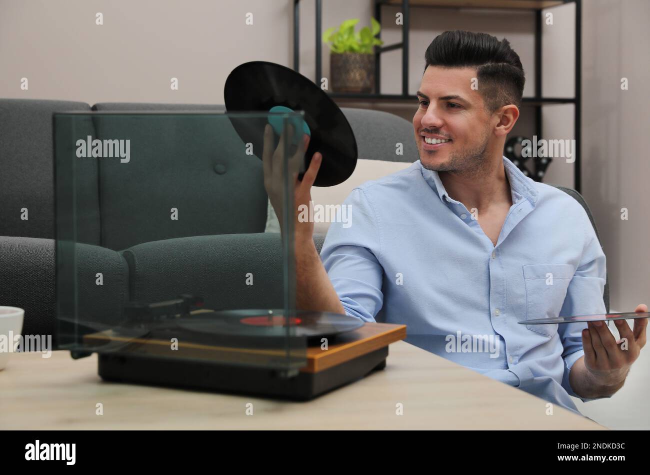 Un uomo felice che sceglie il disco in vinile per giocare con il giradischi a casa Foto Stock