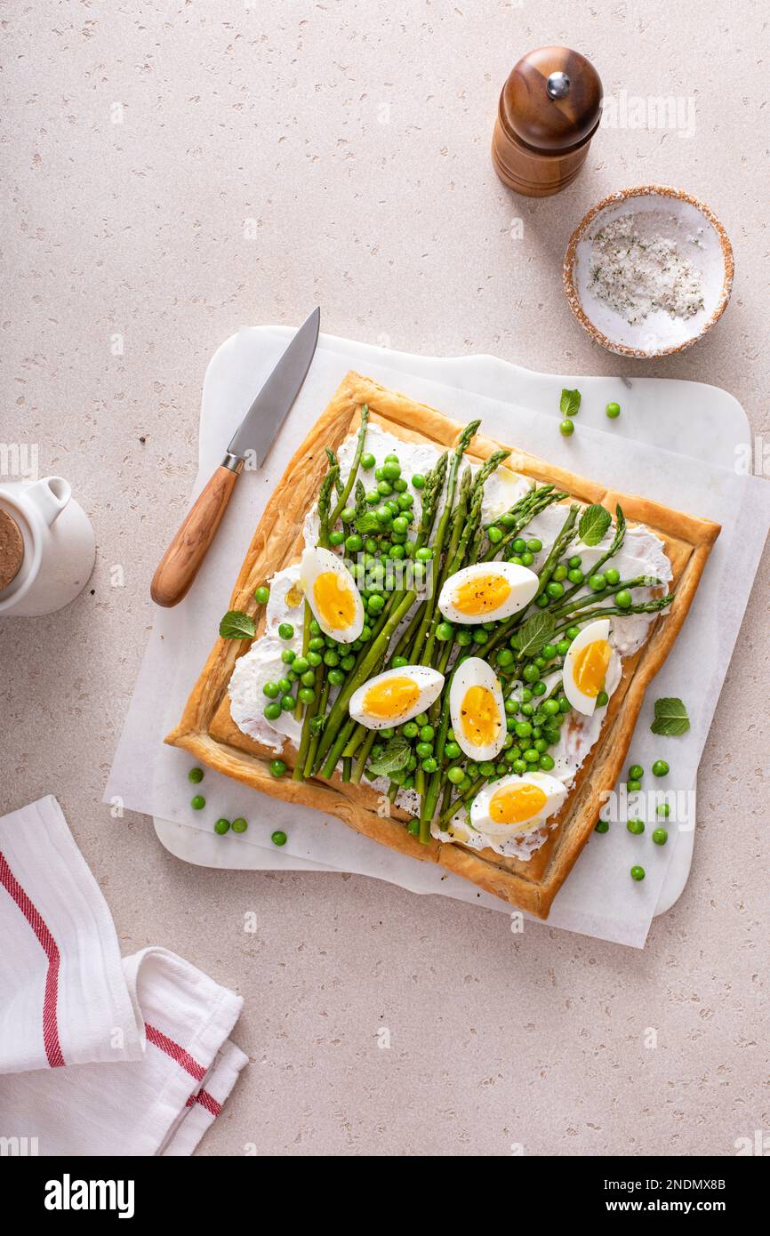Crostata di primavera fresca con piselli verdi, uova sode e asparagi sulla pasta sfoglia vista dall'alto Foto Stock