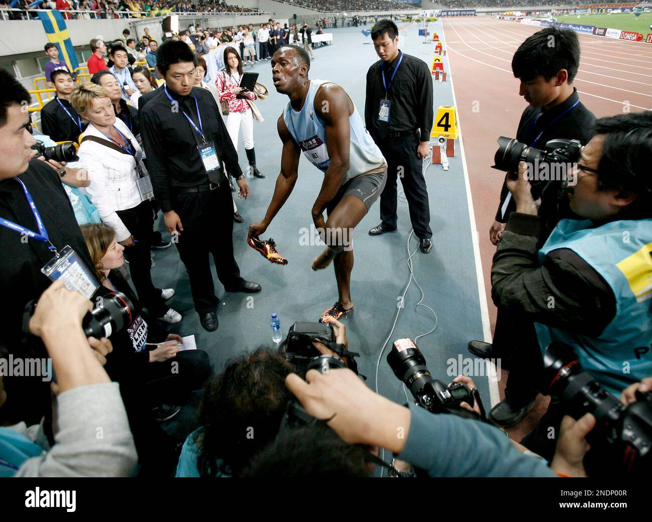 Usain Bolt of Jamaica, center, is surrounded by security and photographers while he take off his shoes after he has won the 200 meters at the IAAF Diamond League in Shanghai, China, Sunday May 23, 2010. (AP Photo/Andy Wong) Foto Stock