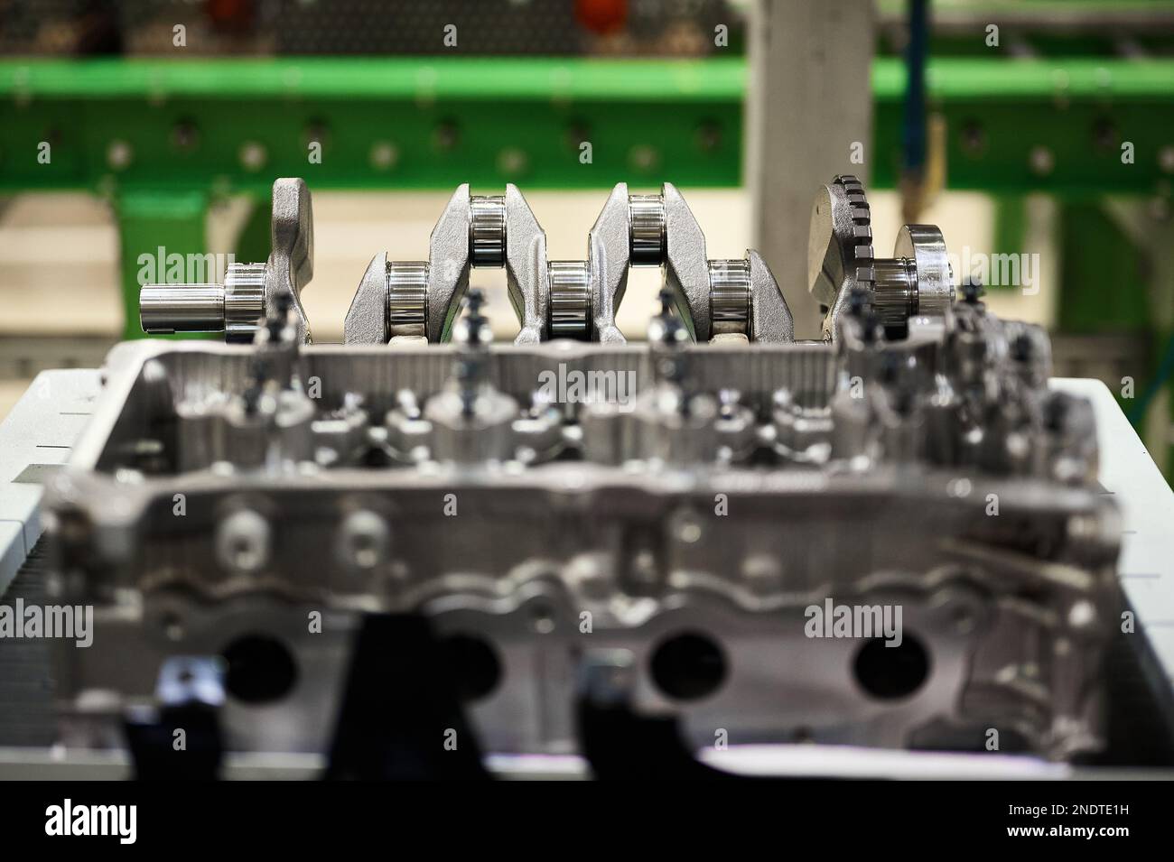 Testa cilindro del motore sfocata contro l'albero motore sul convogliatore Foto Stock