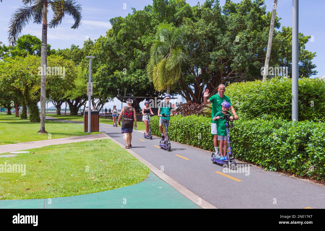 Uomo maturo e bambini che cavalcano e-scooter sulla Esplanade, Cairns, far North Queensland, FNQ, QLD, Australia Foto Stock