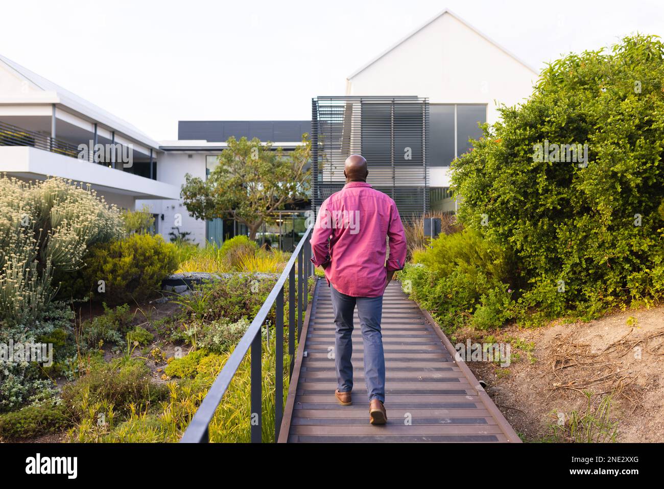 Vista posteriore dell'uomo anziano afro-americano che cammina sul sentiero del giardino. stile di vita e concetto di vita senior in pensione Foto Stock