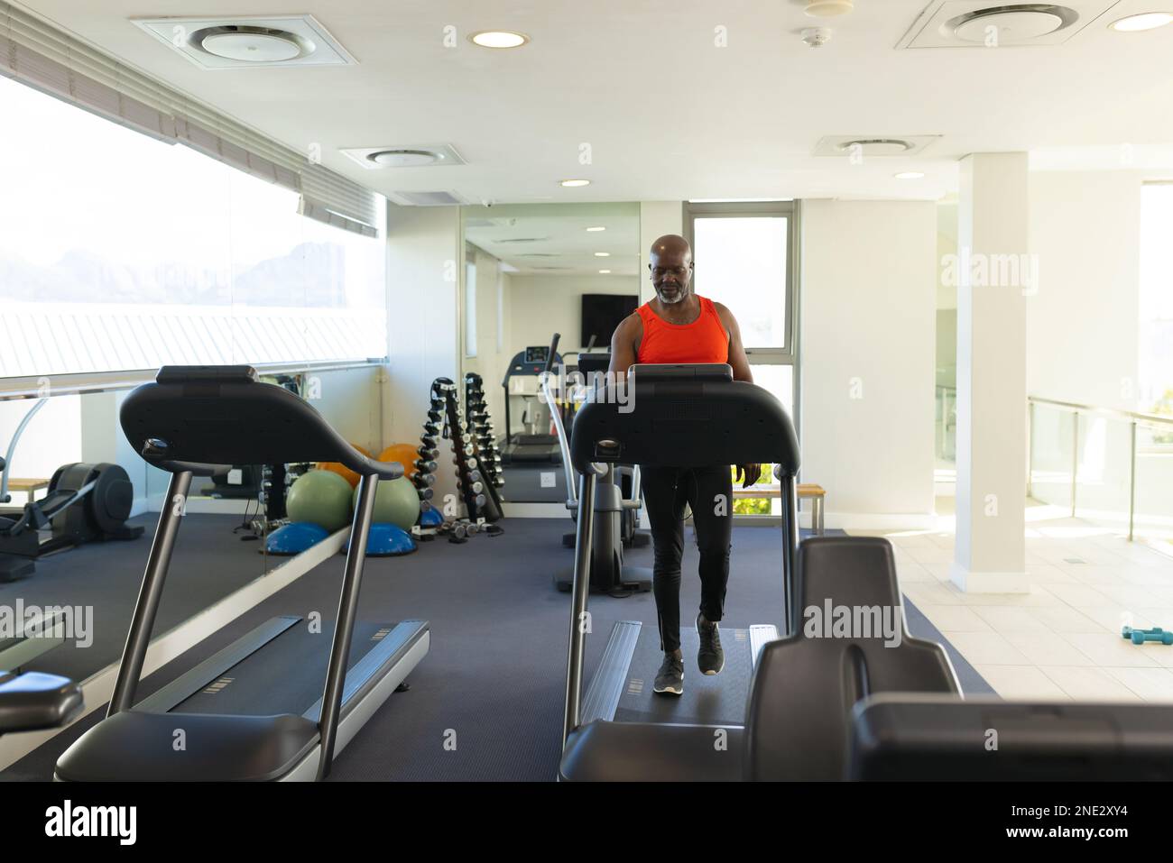 Uomo anziano afroamericano che cammina su un tapis roulant presso la palestra. stile di vita e concetto di vita senior in pensione Foto Stock