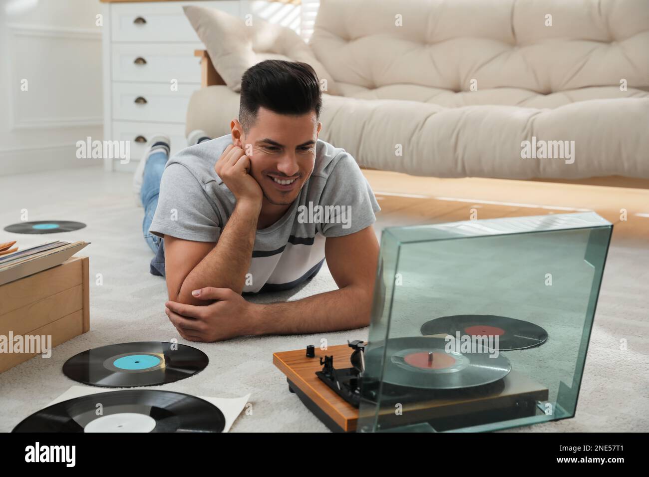 Uomo che ascolta la musica con il giradischi mentre si sdraiava a casa Foto Stock
