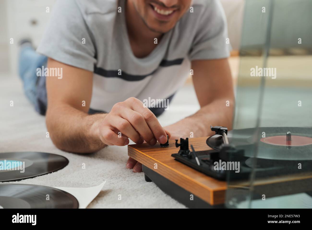 Uomo felice che usa il giradischi a casa, primo piano Foto Stock