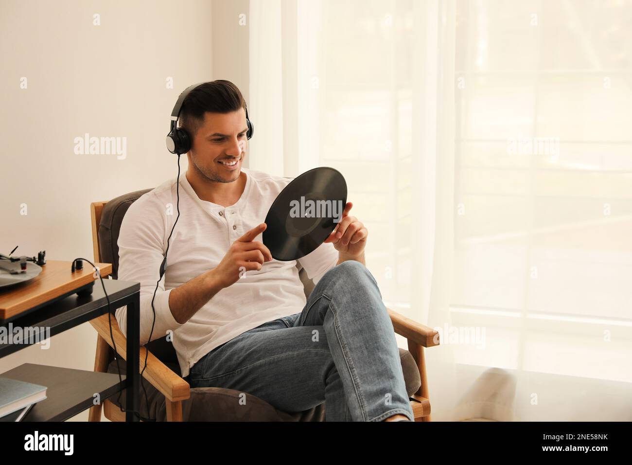 Un uomo felice che ascolta la musica con il giradischi a casa Foto Stock