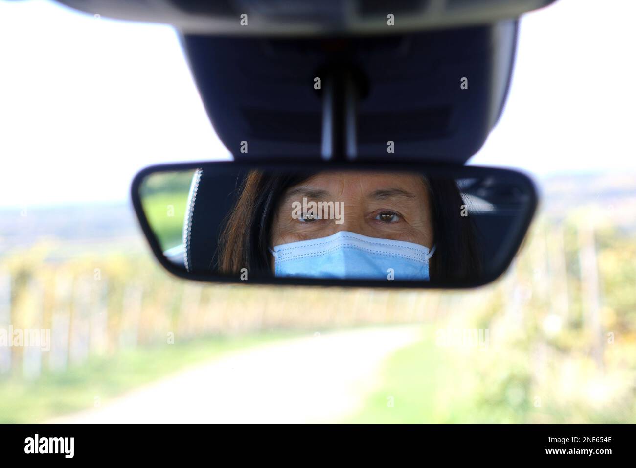 donna con maschera protettiva alla guida di un'auto Foto Stock