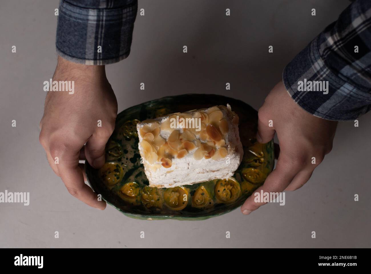 L'uomo tiene in mano un piatto con torta cremosa alle mandorle Foto Stock