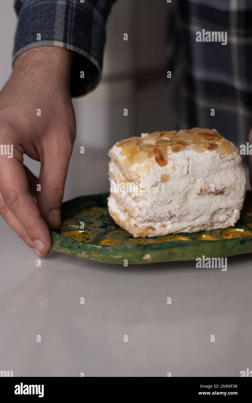 L'uomo tiene un piatto con una torta cremosa alle mandorle Foto Stock
