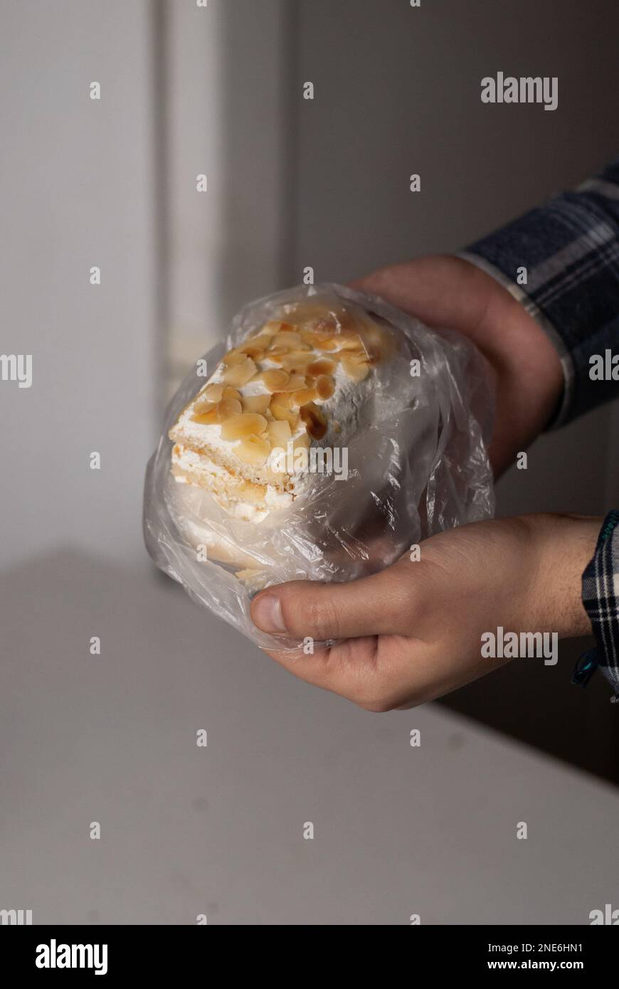 Pezzo di torta cremosa con mandorle in mano Foto Stock