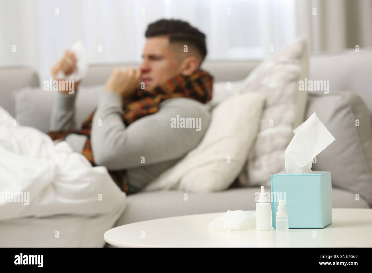 Malato uomo a casa, concentrarsi su spray nasale, gocce e scatola di tessuti Foto Stock