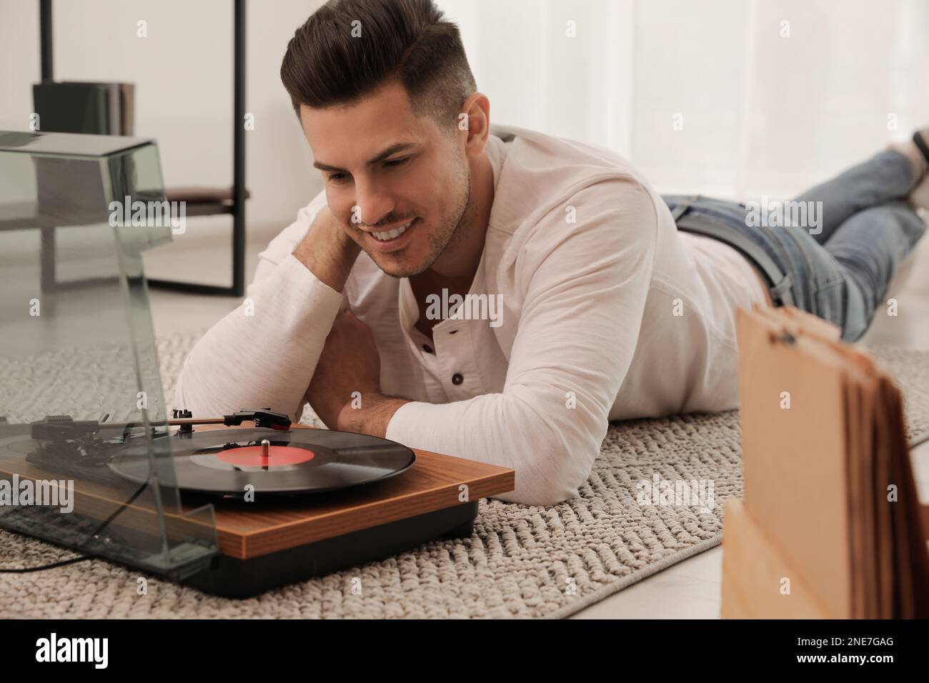 Uomo felice che ascolta musica con il giradischi mentre si sdraiava a casa Foto Stock