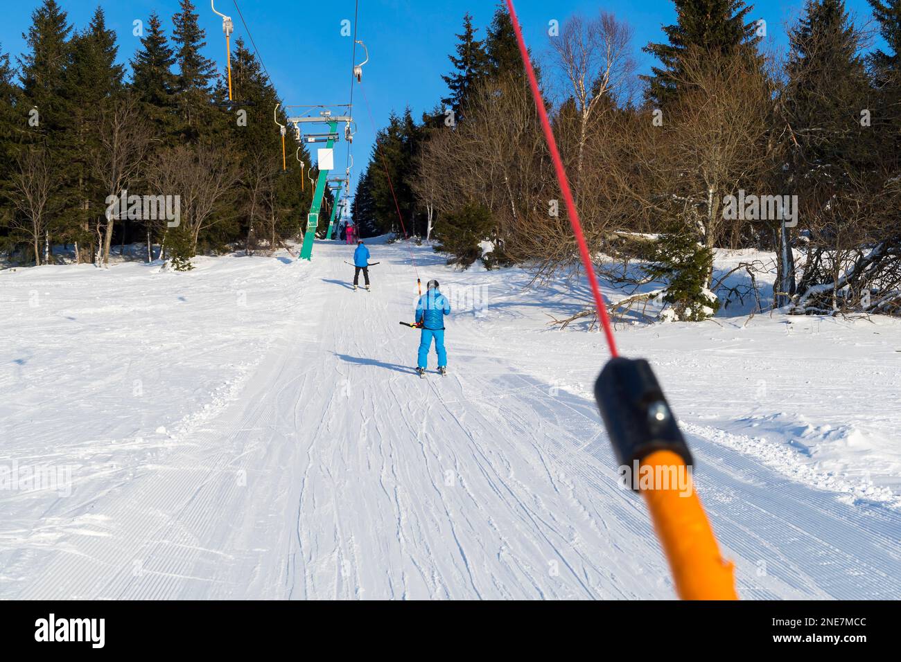 Sciatori sul T-bar ski lift nella soleggiata giornata invernale Foto Stock