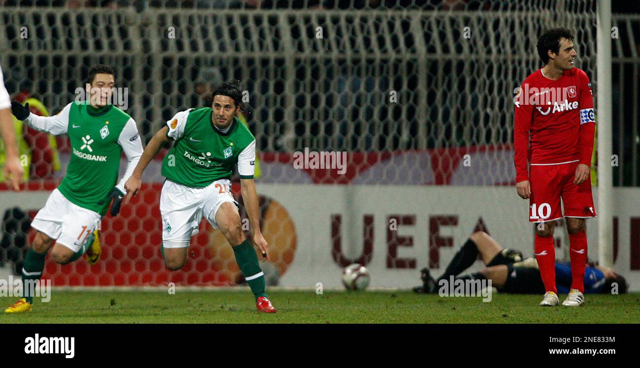 Bremen's Claudio Pizarro and Mesut Oezil, left, celebrate after scoring while Twente's Kenneth Perez , right, looks on during their Europa League second leg soccer match between Werder Bremen and Twente Enschede in Bremen, Germany, Thursday, Feb. 25, 2010. (AP Photo/Frank Augstein) Foto Stock