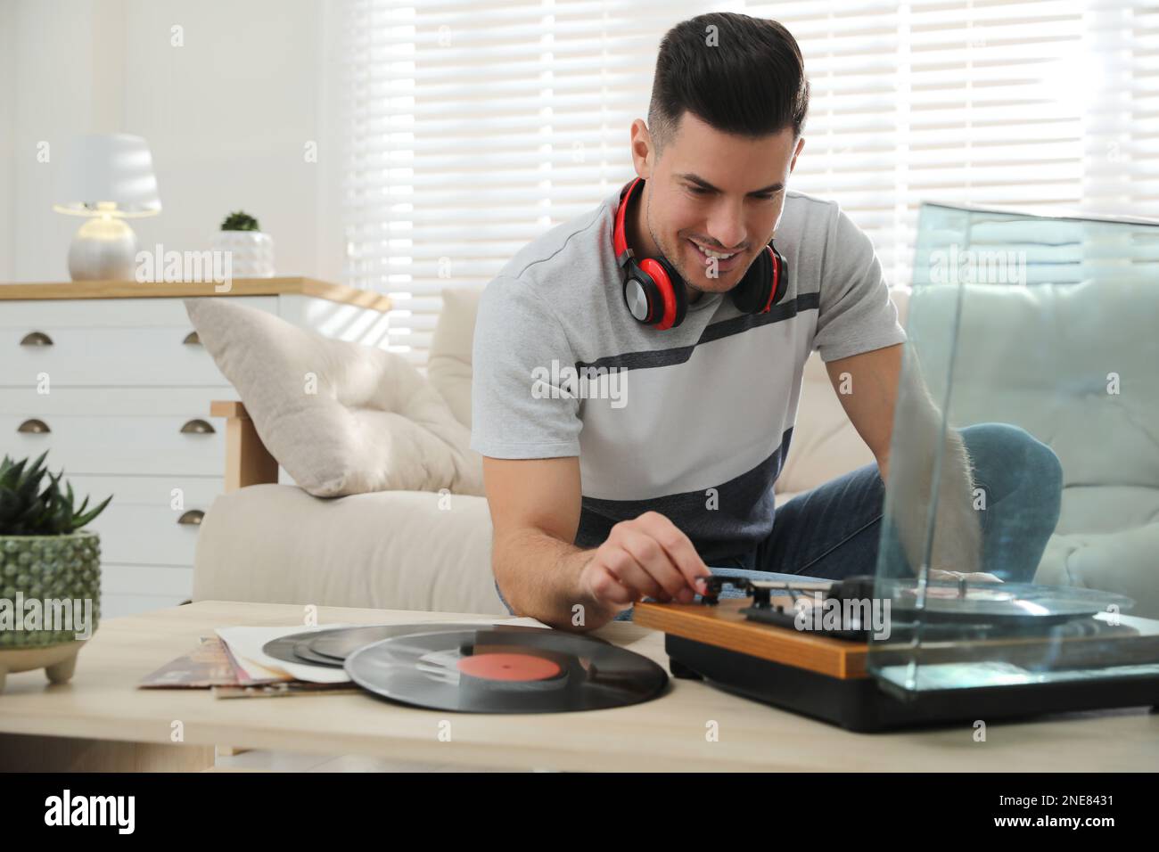 Un uomo felice che ascolta la musica con il giradischi a casa Foto Stock
