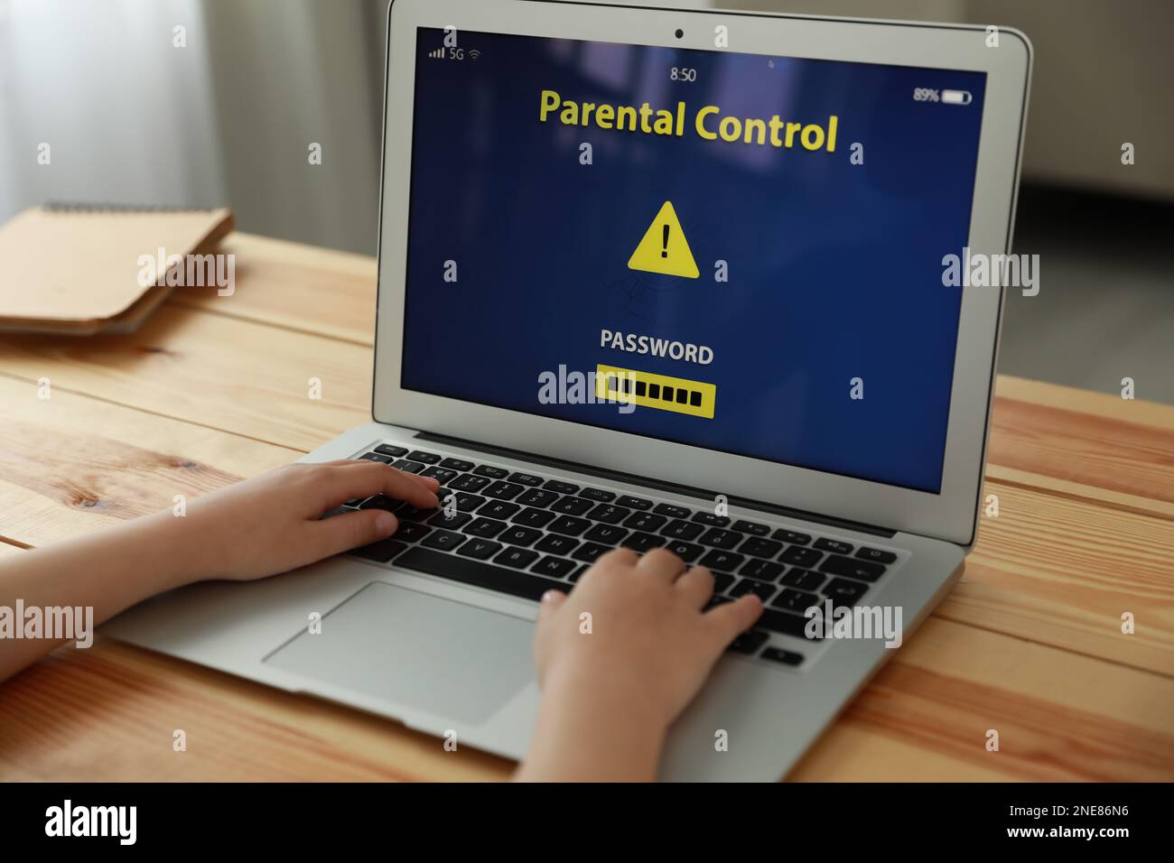 Bambino che utilizza un computer portatile con l'app di controllo genitori installata a casa, primo piano. Sicurezza informatica Foto Stock