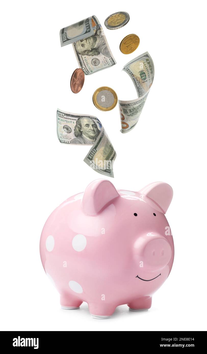 Banconote e monete che cadono in una banca di porcellini su sfondo bianco. Risparmio di denaro Foto Stock