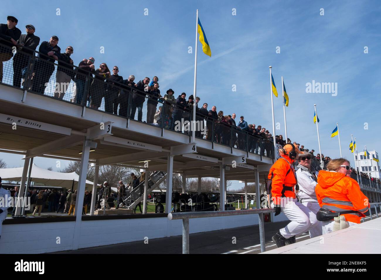 Spettatori in piedi sul tetto di Pit Lane e marescialli seduti sul muro di Pit Lane, 79th Members' Meeting, circuito automobilistico di Goodwood, Regno Unito Foto Stock