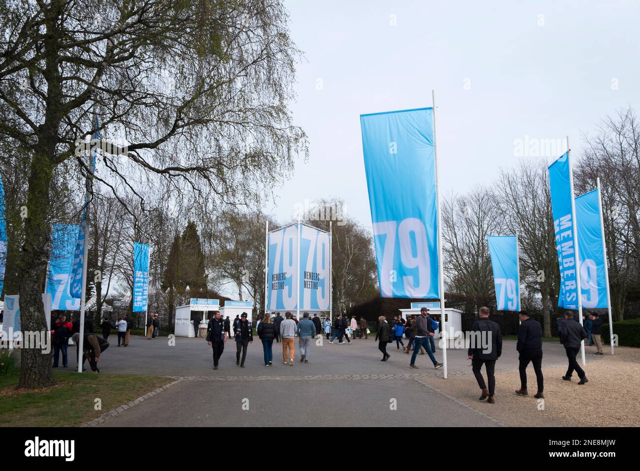 Spettatori che passavano davanti ai grandi striscioni blu all'ingresso del Members' Meeting 79th, circuito automobilistico di Goodwood, Chichester, West Sussex, UK Foto Stock