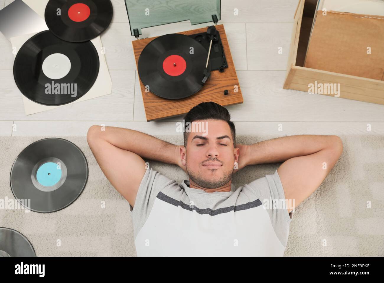 Uomo che ascolta la musica con il giradischi mentre si sdraiava a casa, sopra la vista Foto Stock