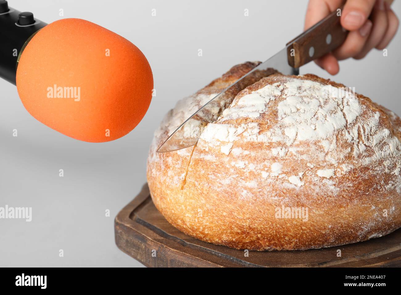 Donna che fa suoni ASMR con microfono e pane su sfondo grigio, primo piano Foto Stock