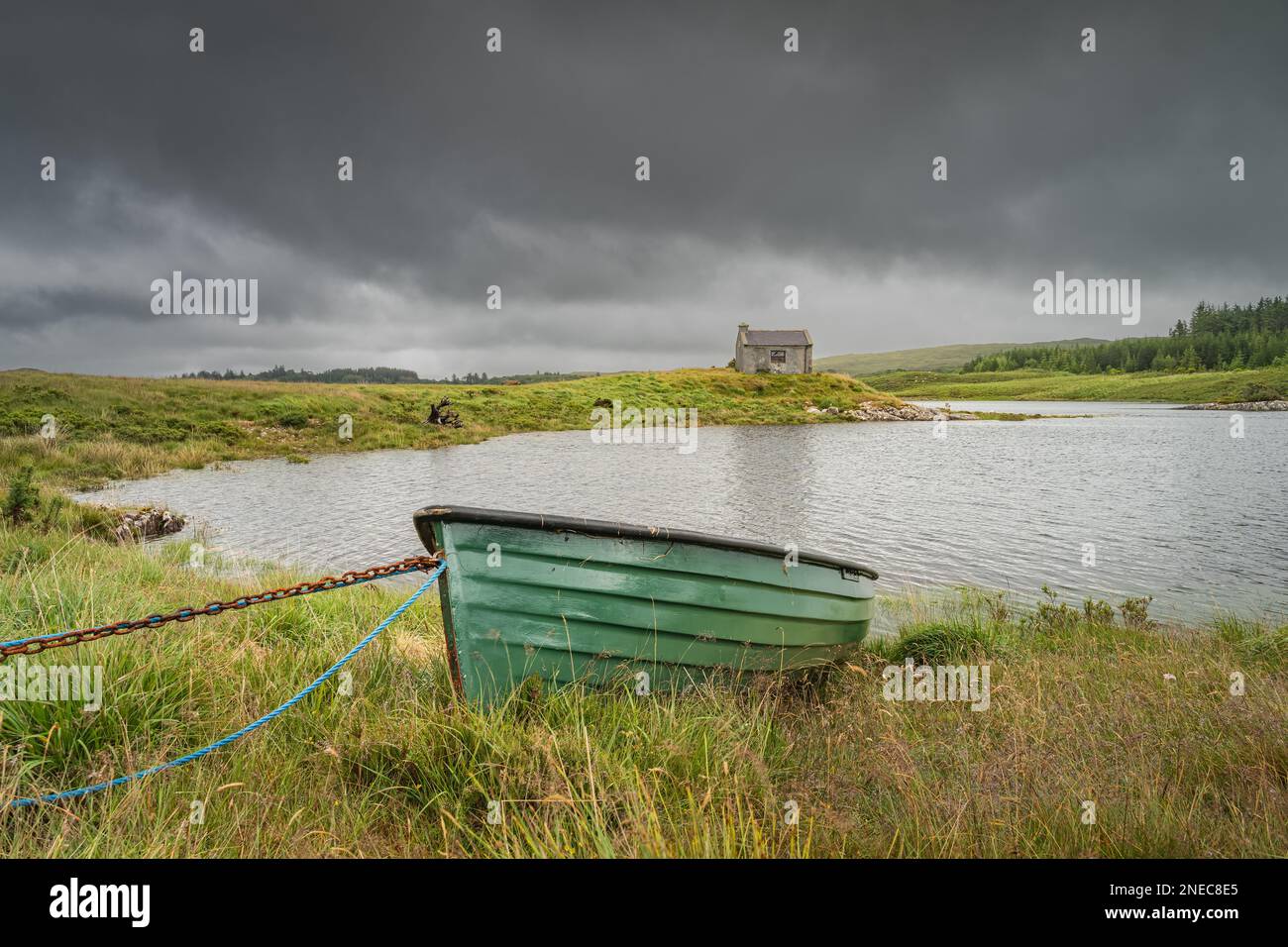 Paddle boat e casa sul bordo del lago Ballynahinch con il cielo scuro e drammatico tempesta sullo sfondo. Connemara, Contea di Galway Foto Stock