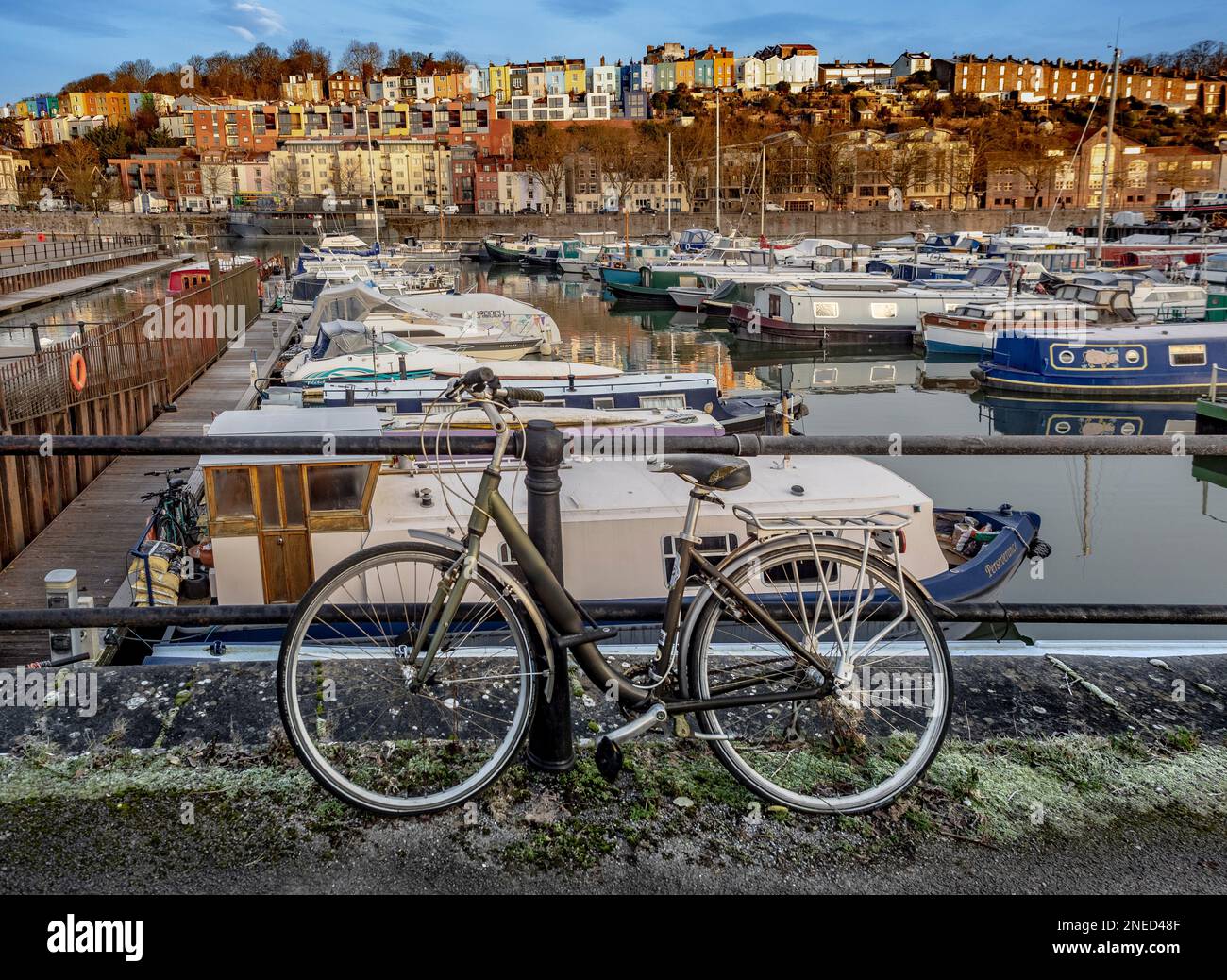 Bicicletta appoggiata su ringhiere in metallo con Bristol Marina e le colorate case Cliftonwood Terrace sullo sfondo, Bristol, Regno Unito Foto Stock