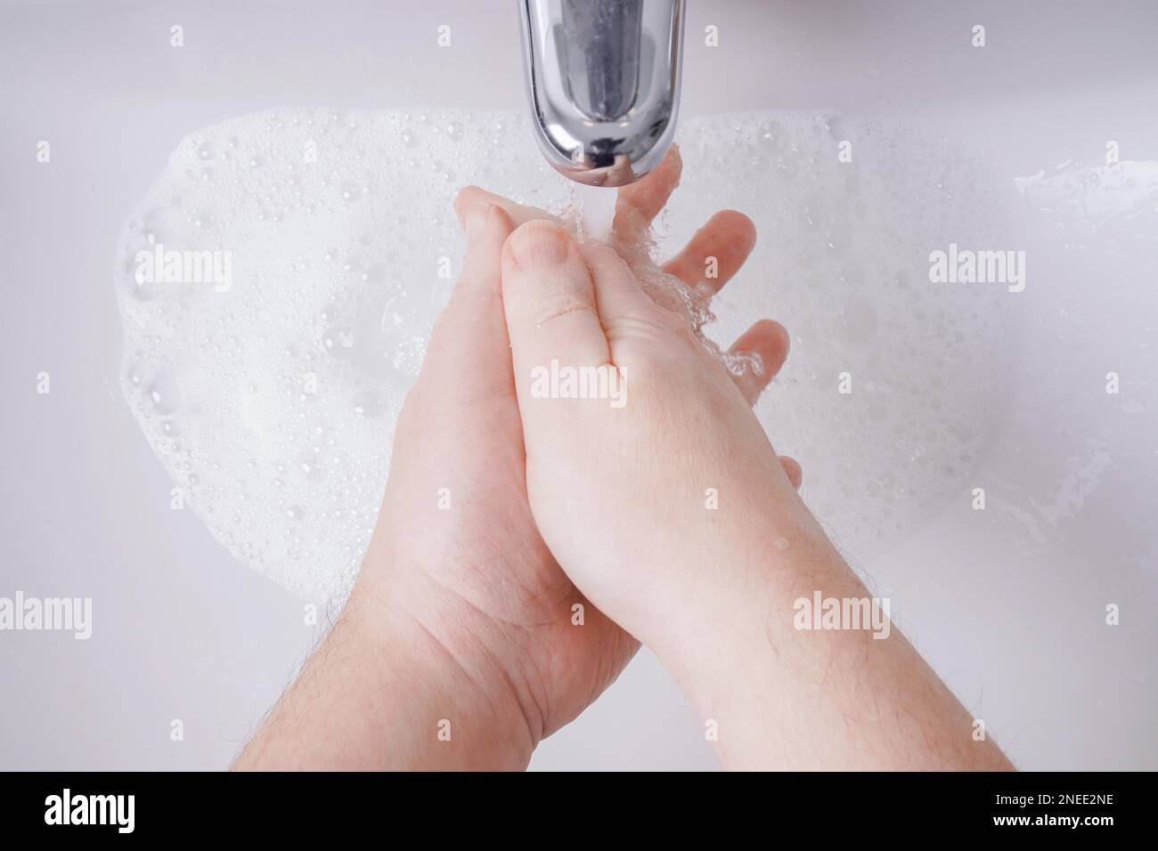 lavando le mani con sapone e acqua dal punto di vista personale - concetto di igiene con persona maschile non riconoscibile e profondità di campo poco profonda Foto Stock