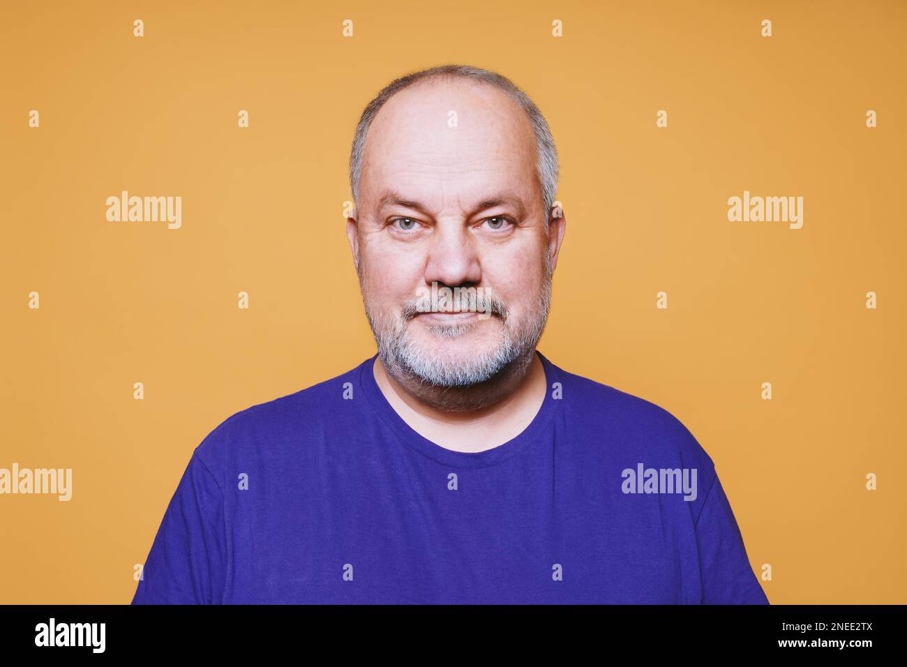 ritratto dell'uomo anziano con i capelli bianchi grigi e. barba sullo sfondo dello studio di colore arancione Foto Stock