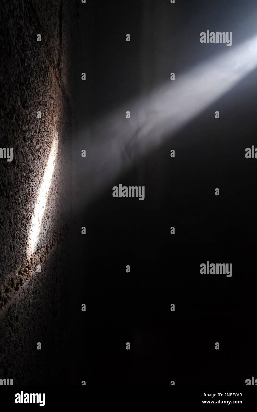 Un raggio di luce che si riflette su una parete di cenere attraverso una stanza fumosa. Foto Stock
