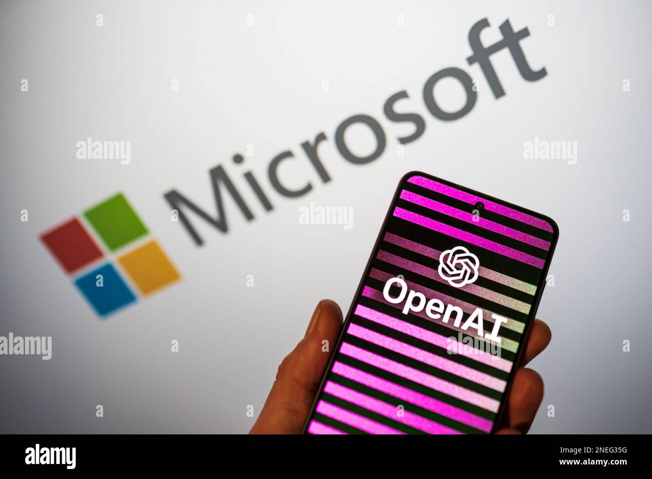 Logo OpenAI sul telefono in una mano e logo Microsoft sfocato sullo sfondo. Bing integra ChatGPT ai chatbot nel motore di ricerca. Varsavia, Polonia - 15 febbraio 2023. Foto Stock