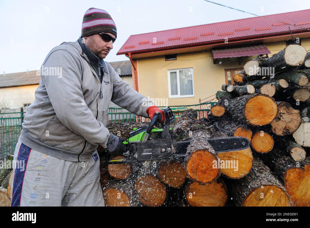 Lviv, Ucraina 16 febbraio 2023. Uomo che taglia legno con motosega. Le persone raccolgono legna da ardere per sopravvivere durante l'inverno durante l'attacco della Russia alle infrastrutture energetiche. La Russia invase l'Ucraina il 24 febbraio 2022, scatenando il più grande attacco militare in Europa dalla seconda guerra mondiale Foto Stock