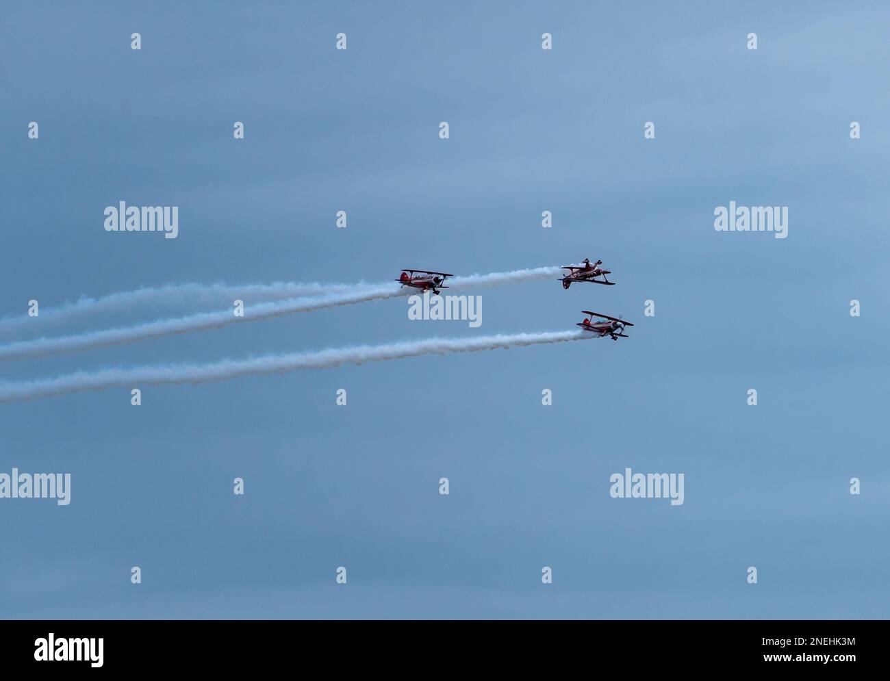 Una squadra acrobatica dell'aviazione che vola vicino mentre esegue acrobazie in biplanari rossi Foto Stock