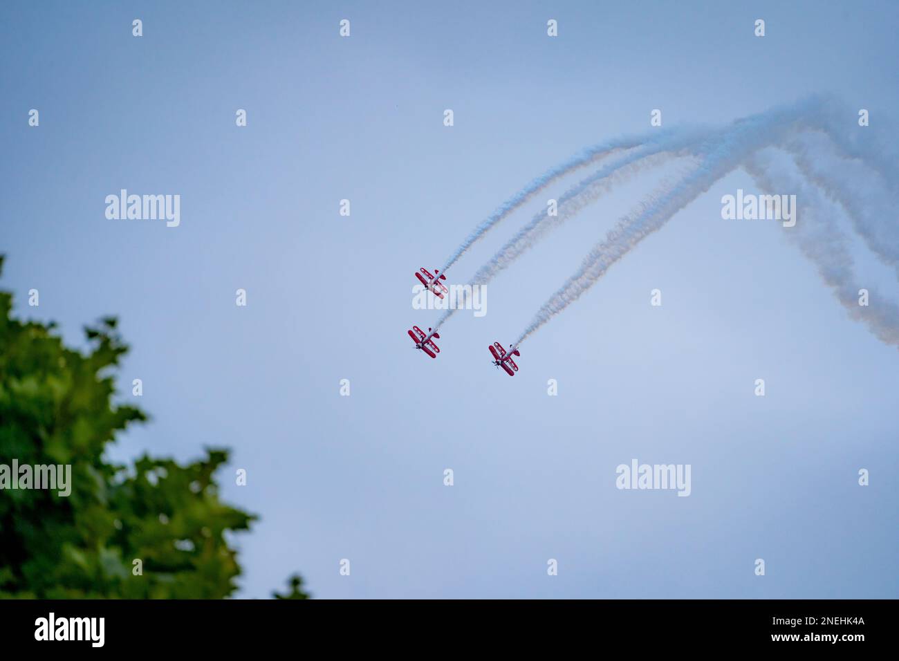 Una squadra acrobatica dell'aviazione che vola vicino mentre esegue acrobazie in biplanari rossi Foto Stock