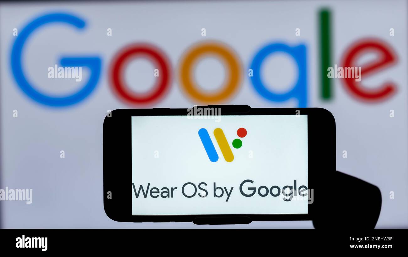 In questa immagine, il logo di Wear OS by Google viene visualizzato sullo schermo di un telefono cellulare con un logo Google sullo sfondo. Foto Stock
