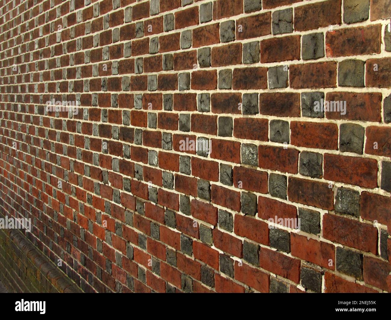I mattoni rossi e grigi si alternano in uno schema lungo un muro nella città vecchia di Filadelfia. Foto Stock