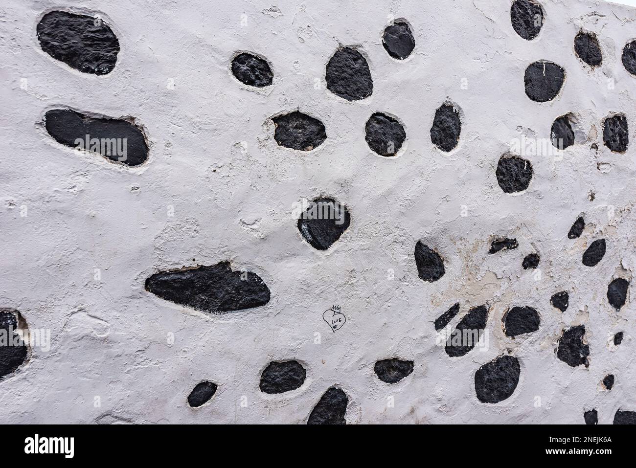 Una caratteristica parete con roccia vulcanica incorporata a Fira, Santorini Foto Stock