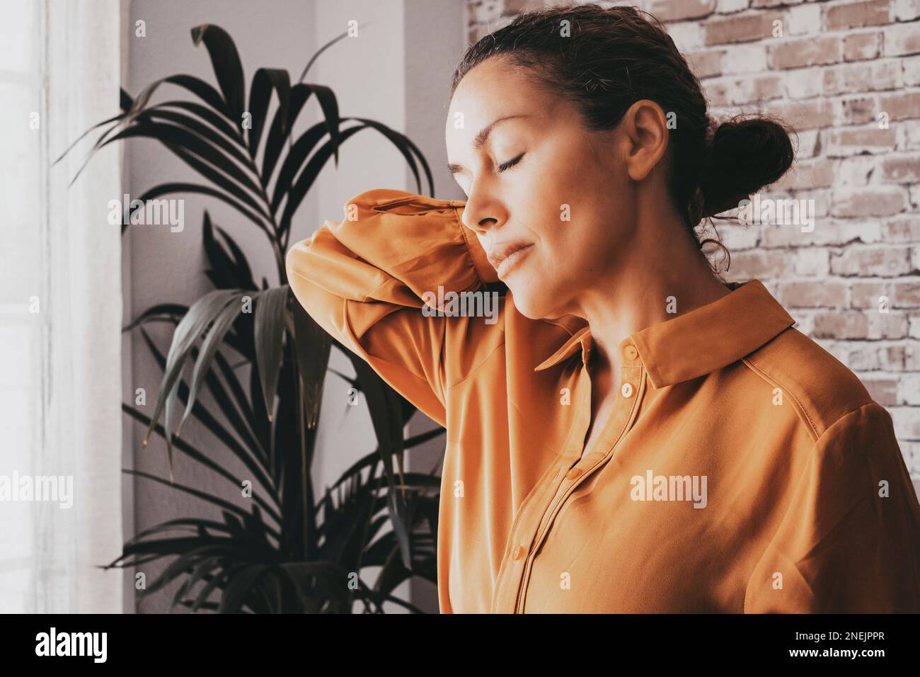 Dolore al collo. Una donna che tocca la spalla a casa o in ufficio. Malattia muscolare. Backpain. Donne di mezza età massaggiando il collo con gli occhi chiusi. Conc Foto Stock