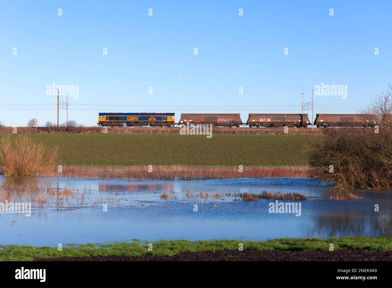GB Raillocomotiva diesel classe 66 66736 treno di trasporto di carri merci a biomassa vuota lungo la linea principale della costa orientale a Newton on Ouse Foto Stock