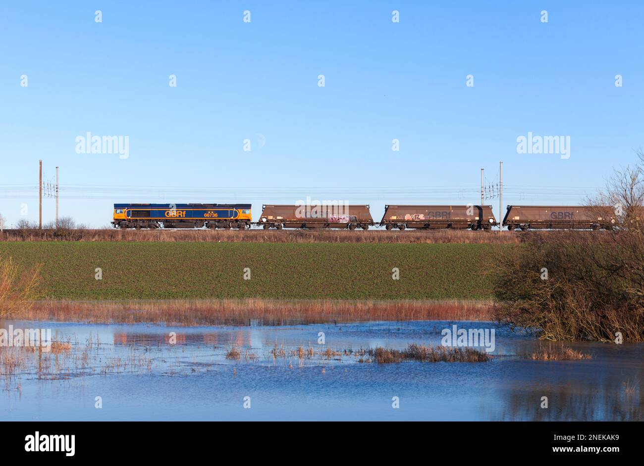 GB Raillocomotiva diesel classe 66 66736 treno di trasporto di carri merci a biomassa vuota lungo la linea principale della costa orientale a Newton on Ouse Foto Stock